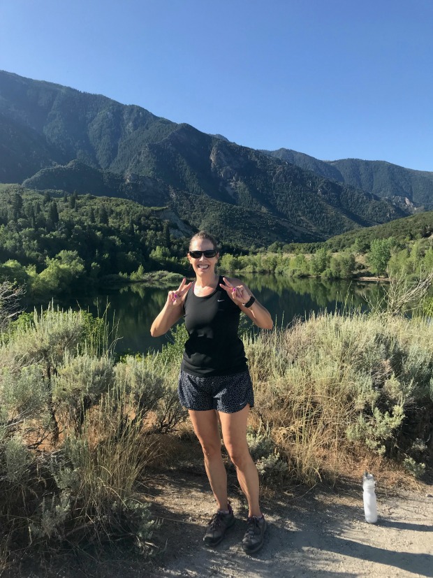 Woman hiking in front of a reservoir.