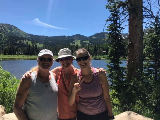 Three adults in front of a lake.