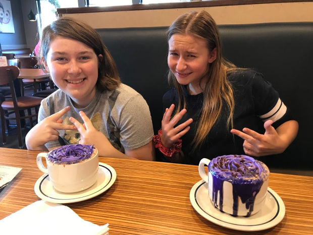 Two teenage girls drinking hot chocolate.