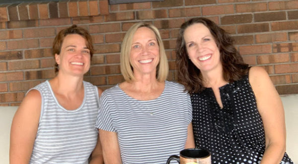 Three adult sisters smiling.
