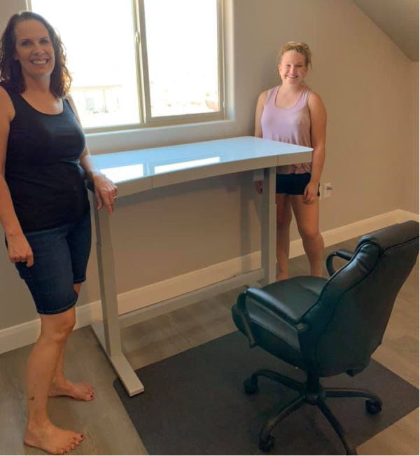 Woman and granddaughter standing by a desk.