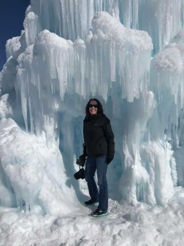 A lady holding a camera in an ice castle.