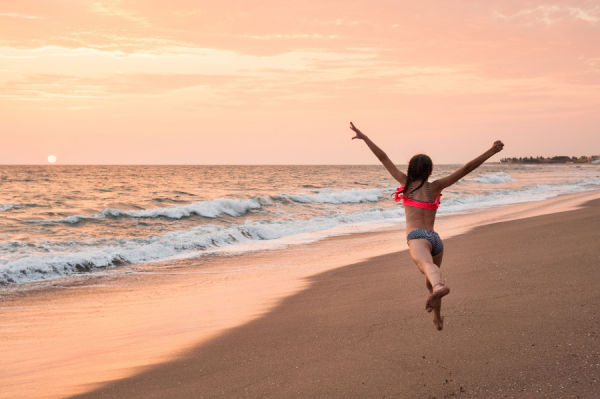 Young girl leaping on the beach at sunset.