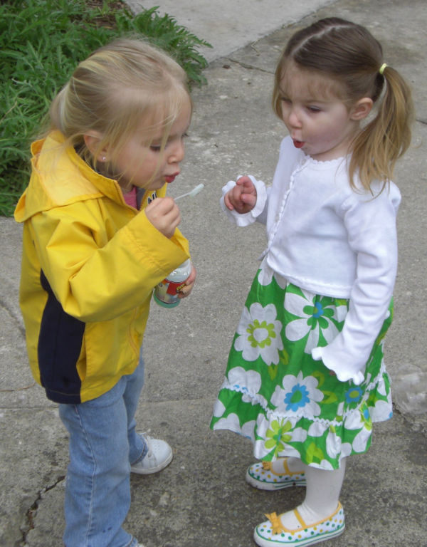 Two young girls blowing bubbles.