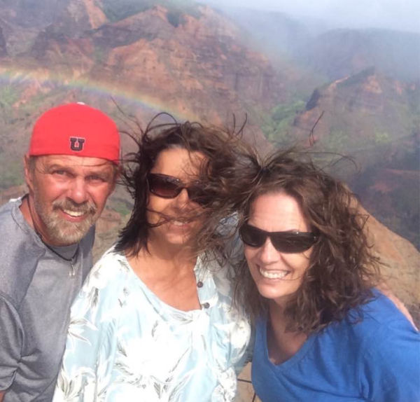 A man and two women in front of a rainbow.