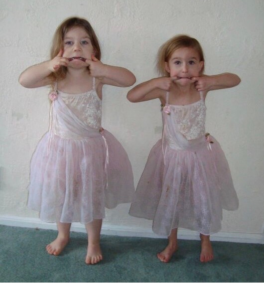 Two young girls in tutus pulling faces.