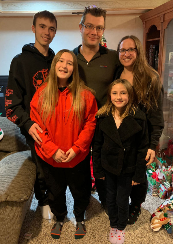 Family of five in front of the Christmas tree.