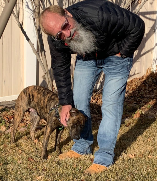 Bearded man petting a young dog.