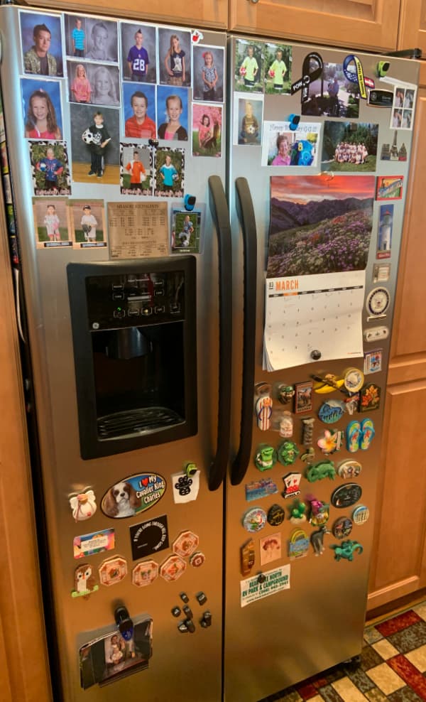 Refrigerator covered in pictures and souvenir magnets.