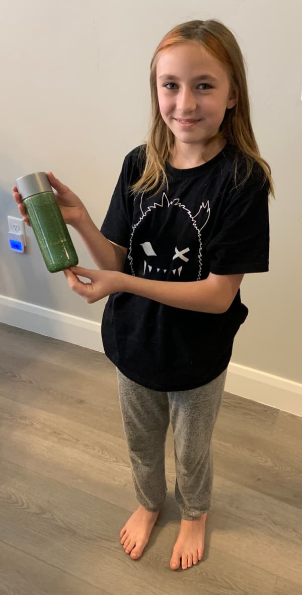 Pre-teen girl holding a green glitter bottle.
