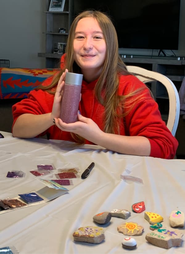 Teenage girl holding a glitter pink bottle.