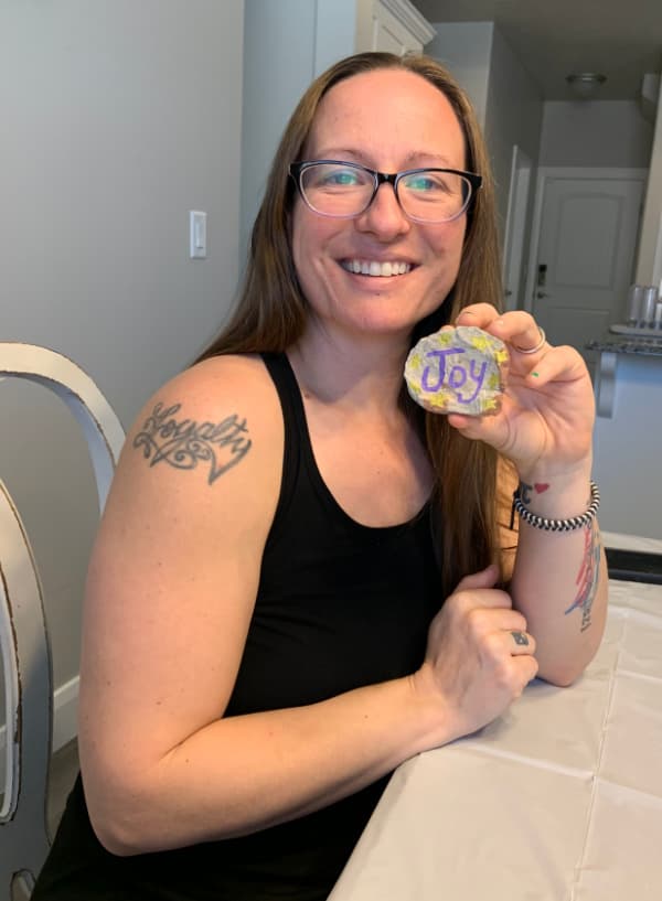 Woman holding a rock that says Joy.