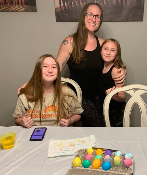 Woman and daughters displaying Easter eggs.
