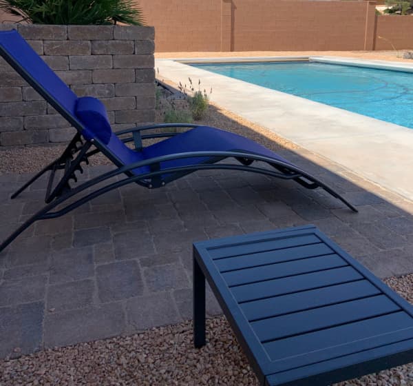 Lounge chair and table by the side of a pool.