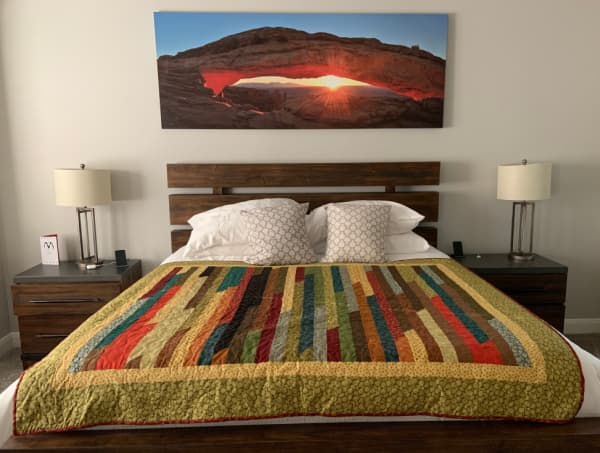 A bed covered by a handmade quilt in desert colors.