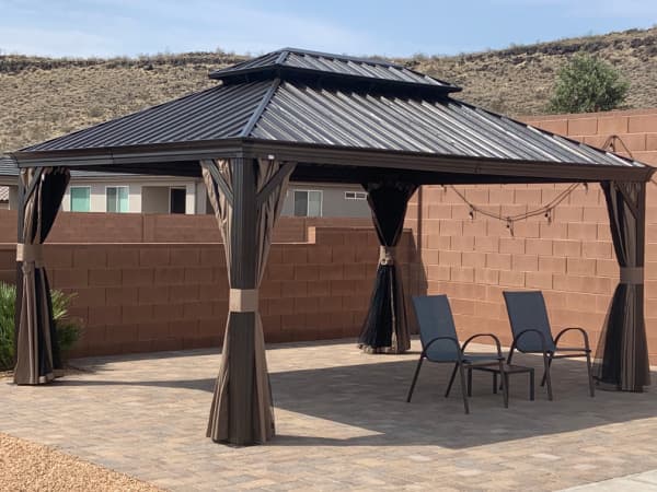 A gazebo and two chairs on a patio.