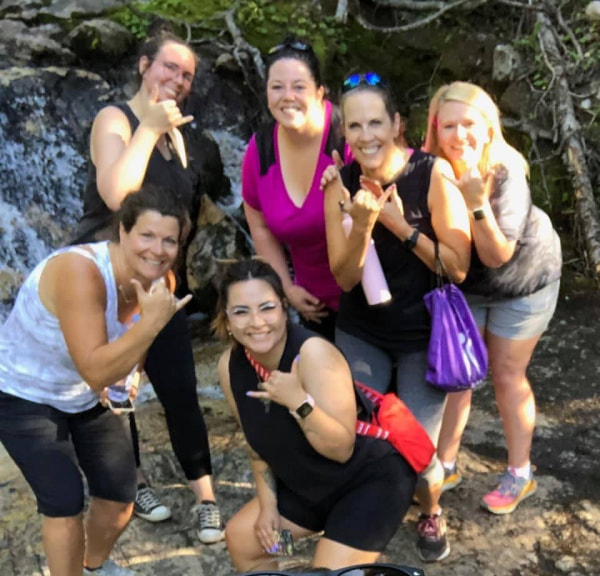 Six ladies standing in front of a waterfall.