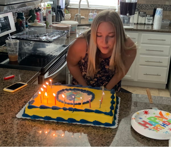 A teenage girl blowing out the candles on her birthday cake.