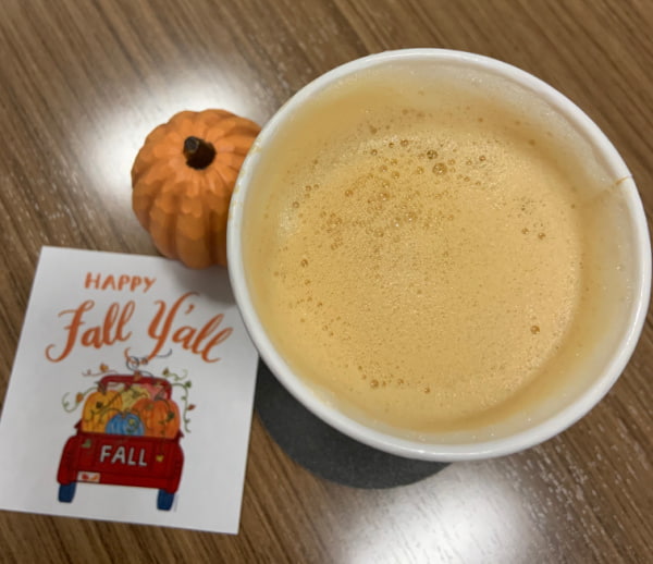 A pumpkin spice latte, a little pumpkin, and a sign that says Happy Fall Y'all.