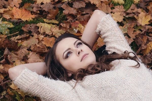 Woman reclined in fall leaves.