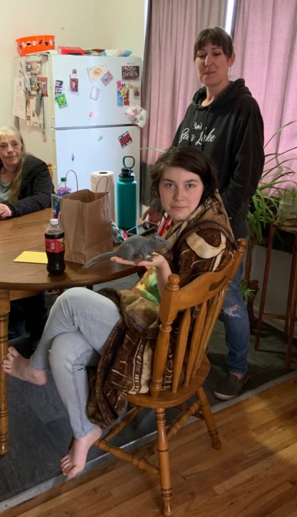 Teenage girl holding a rubber rat.