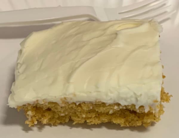 A piece of pumpkin cake with cream cheese frosting.