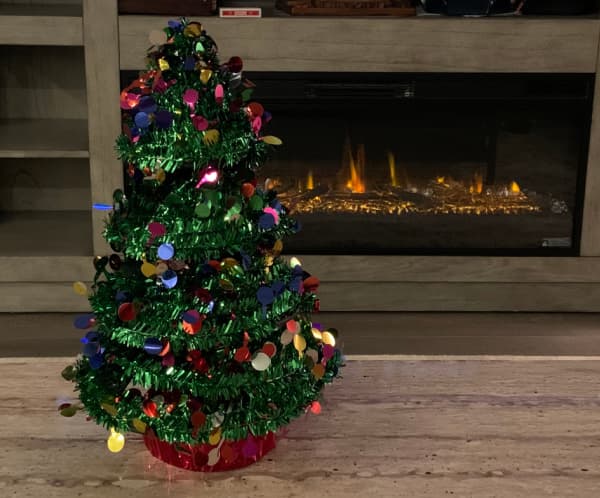 Small Christmas tree in front of a fireplace.