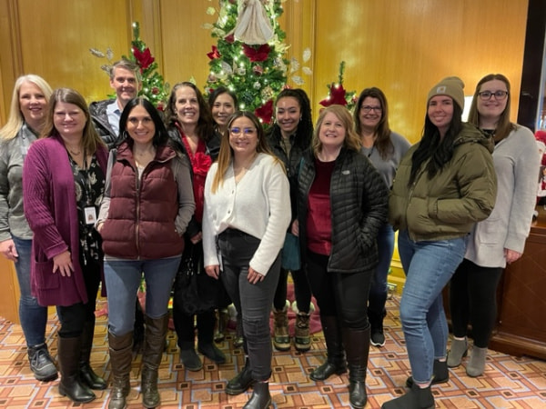 A group of coworkers in front of a Christmas tree.