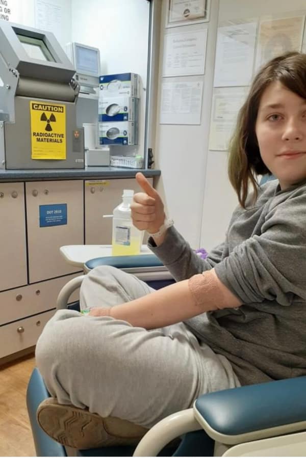 Teenager giving thumbs up in a doctor's office.