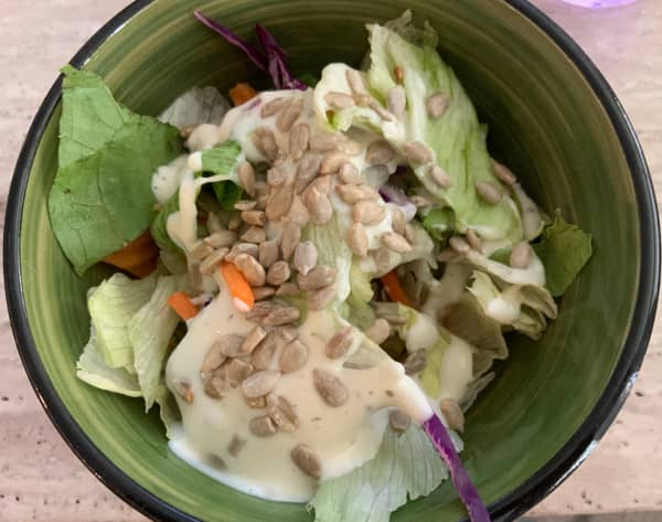 Green salad with ranch dressing and sunflower seeds.