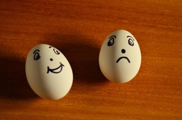 Two eggs, one with smiling face and one with a frowning face.