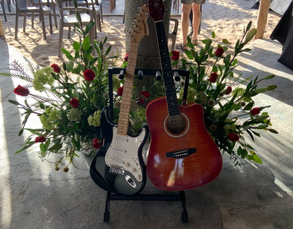 Two guitars in front of a spray of red roses.