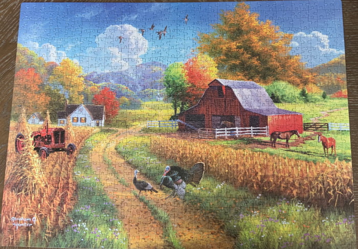 Completed jigsaw puzzle of a barn in autumn.