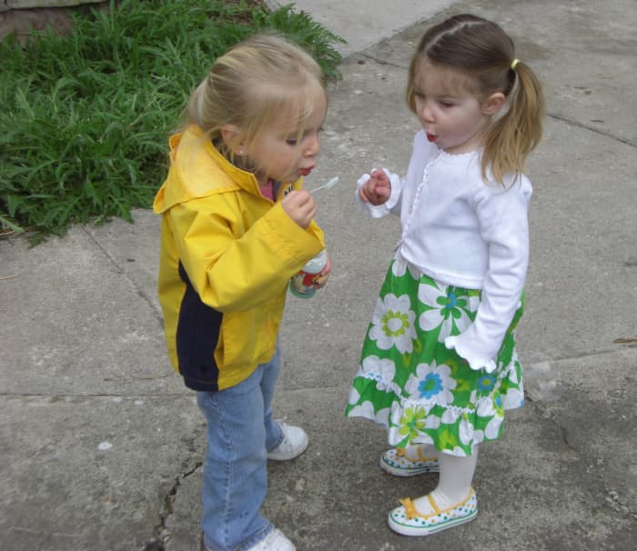 Two young girls blowing bubbles.