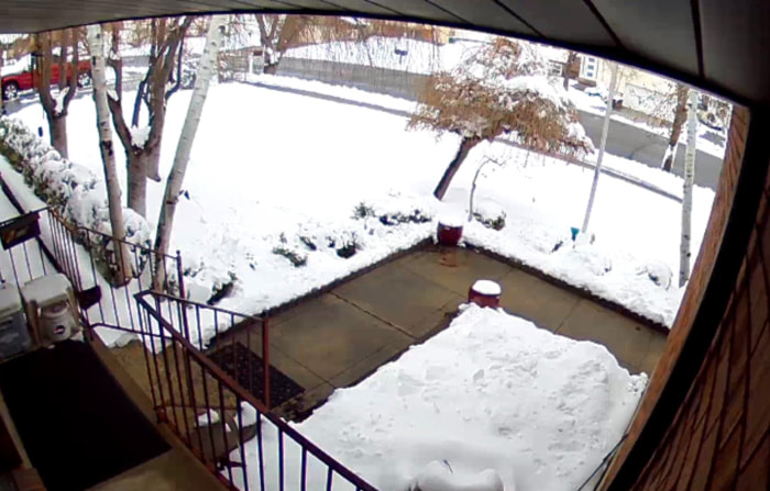 Snow-covered yard as seen from the doorbell camera.