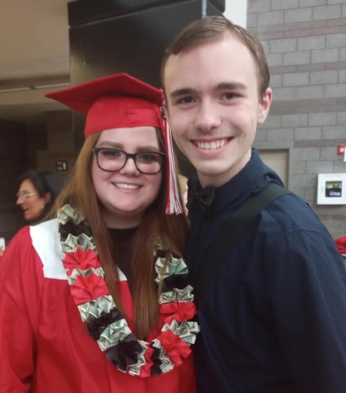 Young woman in a red cap and gown with boyfriend.