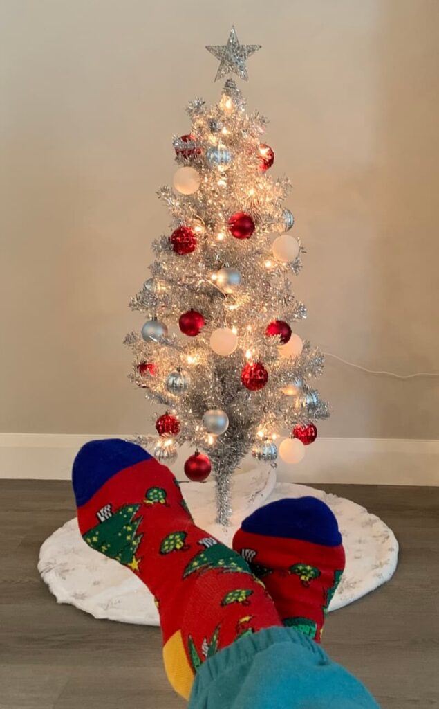 Feet with Christmas socks in front of a Christmas tree.