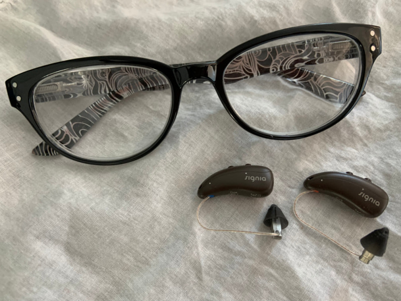 Signia hearing aids next to a pair of glasses.