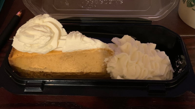 A slice of pumpkin cheesecake with whipped cream.