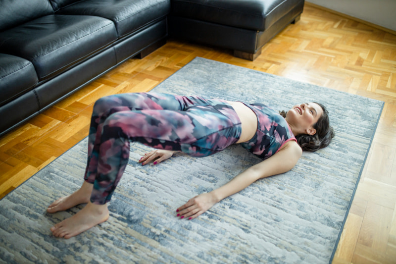 A woman doing a bridge exercise in her home.