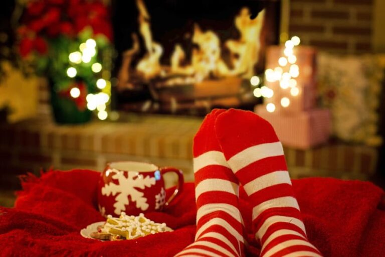 Red and white striped socks and a Christmas mug in front of a fireplace.