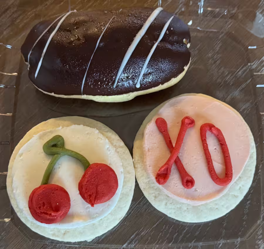 A chocolate eclair and two decorated sugar cookies.