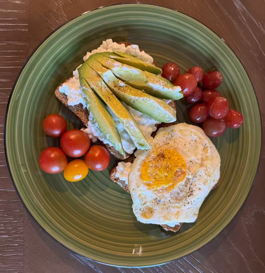 Avocado and cottage cheese toast with a fried egg and cherry tomatoes.