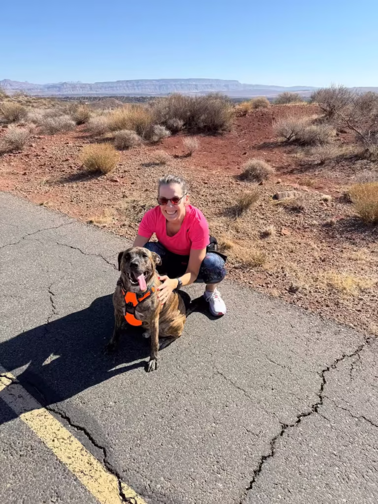 A woman posing with her dog on a walking trail.