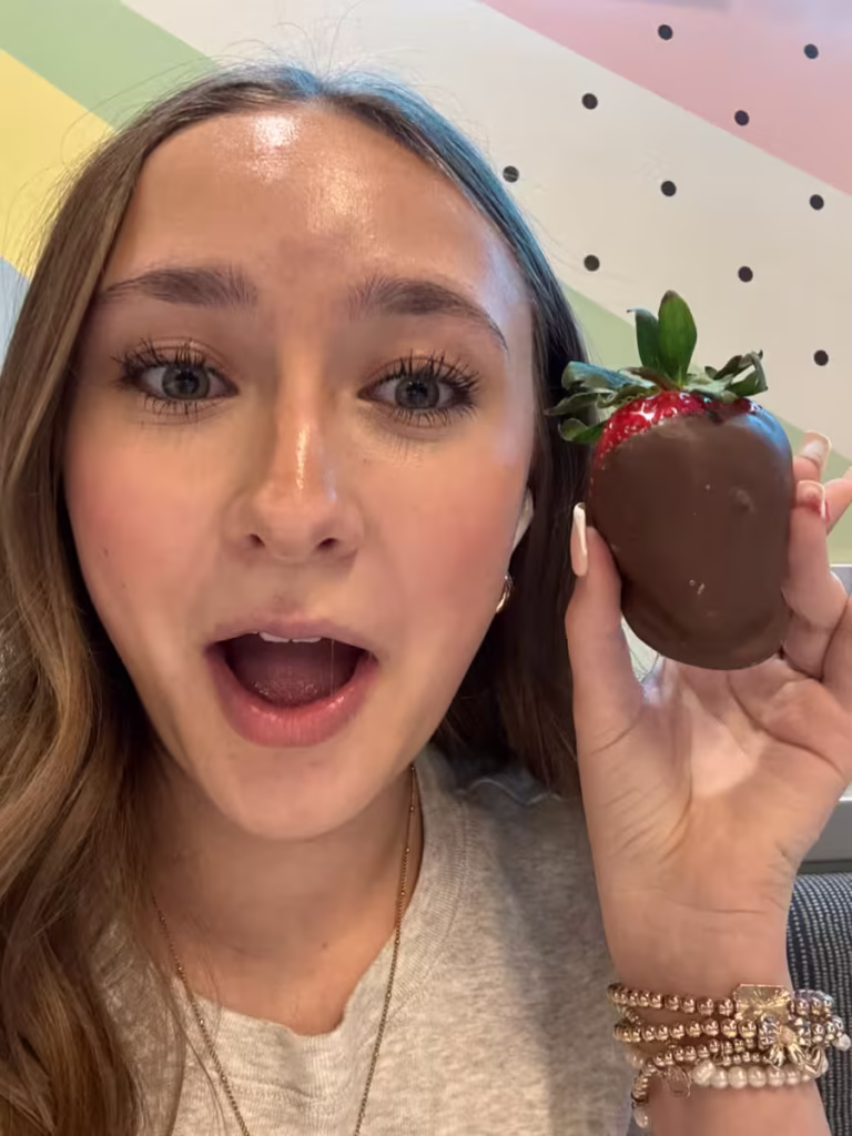 Teenage girl with a large chocolate-covered strawberry.