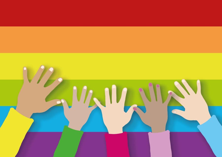 Pride flag with hands of different colors waving.