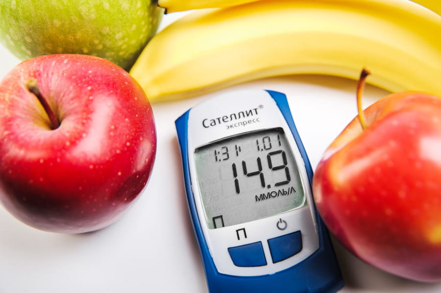 Blood sugar monitor surrounded by bananas and apples.