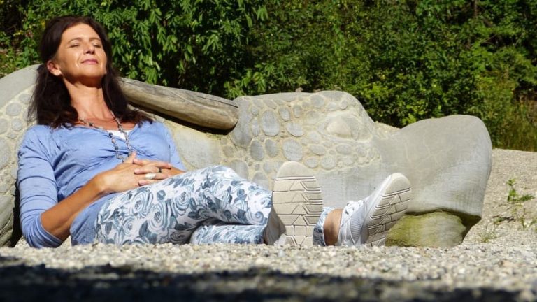 Middle aged woman reclining on a bench.