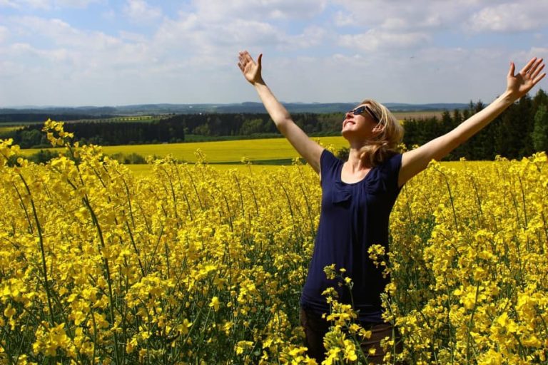 Woman in a field with her arms open in gratitude.