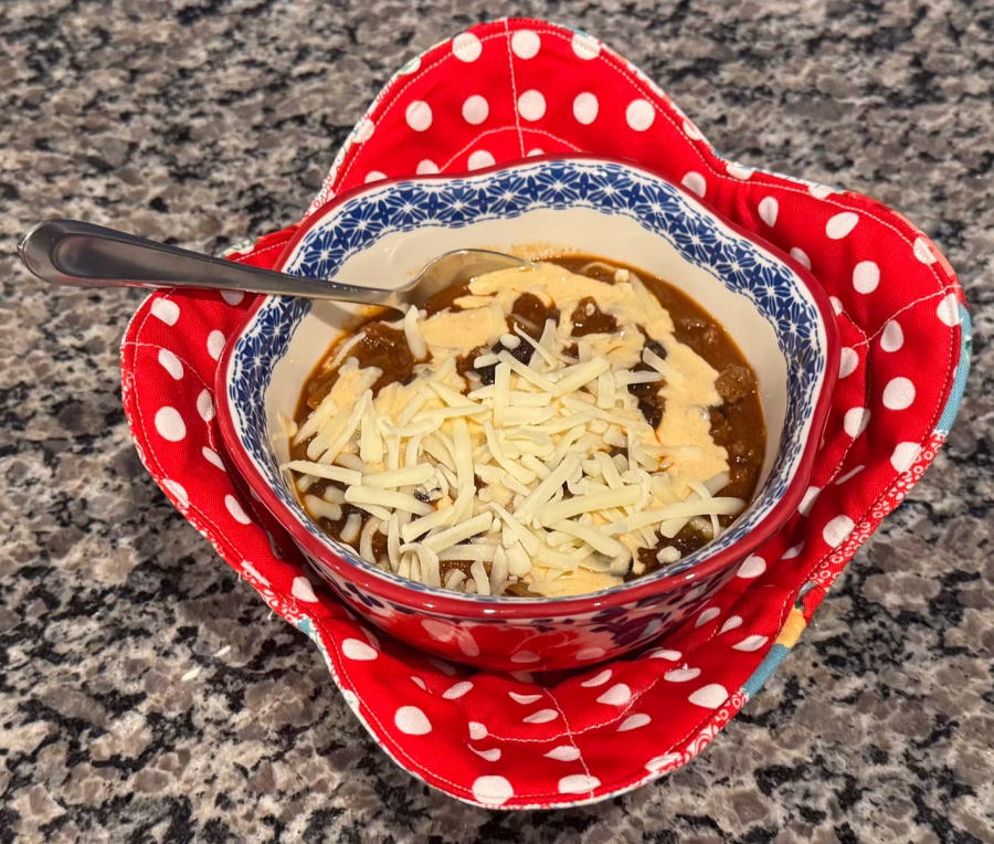 A bowl of chili with cheese on top.